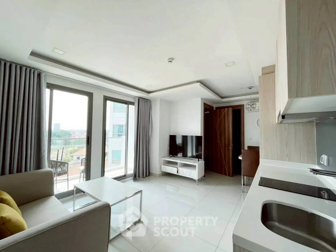 Modern open-plan living room with sleek kitchen and balcony view.