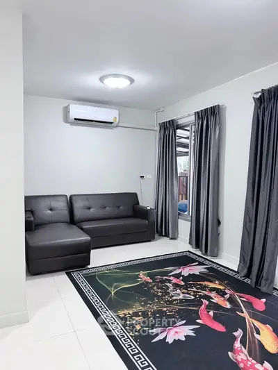 Modern living room with sleek black sofa and vibrant floral rug, featuring natural light and elegant curtains.