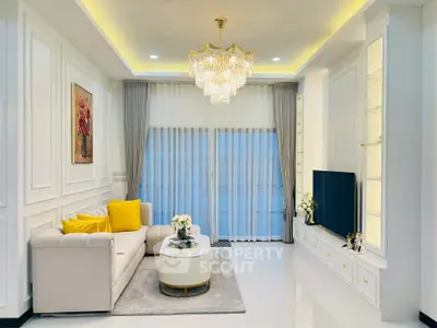 Elegant living room with chandelier, modern decor, and large TV in luxury home.