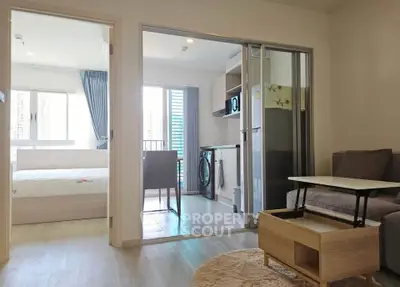 Modern apartment interior with open kitchen and cozy living area, featuring a bedroom with natural light.
