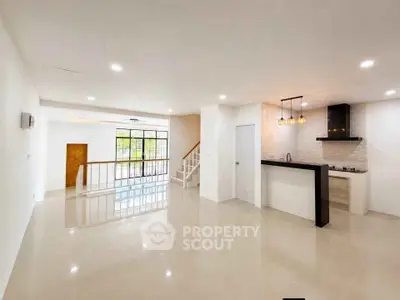 Spacious open-plan living room with modern kitchen and elegant staircase
