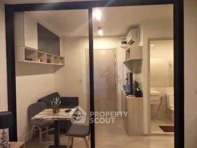 Modern compact living room with dining area and adjacent bathroom in cozy apartment.