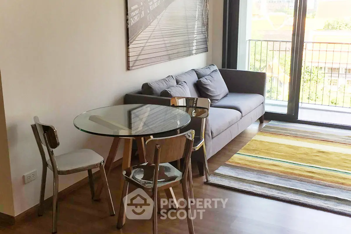 Modern living room with glass table, cozy sofa, and balcony view in a stylish apartment.