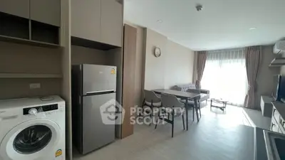 Modern open-plan living room with kitchen, featuring washing machine and fridge, perfect for urban living.