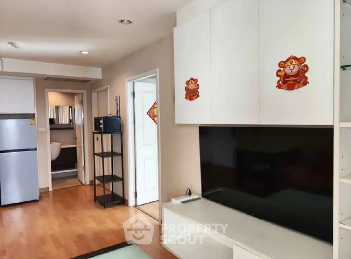 Modern living room with sleek TV unit and open kitchen layout, perfect for cozy urban living.