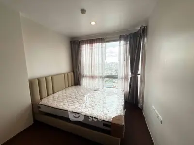 Cozy bedroom with large window offering stunning city views, featuring a comfortable bed and elegant curtains.