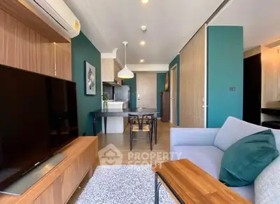 Modern living room with stylish decor and open kitchen layout, featuring a cozy sofa and large TV.
