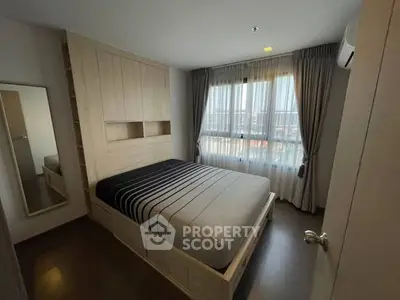 Cozy bedroom with modern design, featuring a comfortable bed and large window for natural light.