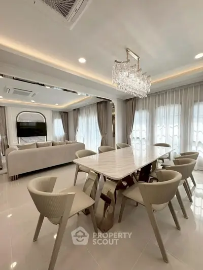 Luxurious open-plan living and dining area with elegant chandelier and modern furniture.