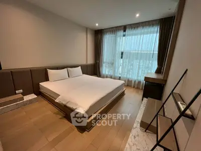 Modern bedroom with large window and wooden flooring, featuring a minimalist design and ample natural light.