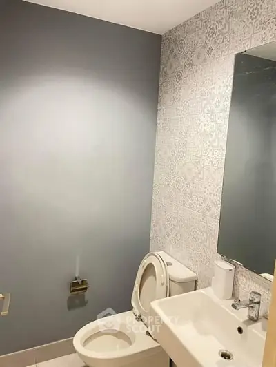 Modern bathroom with stylish patterned wall and sleek fixtures.