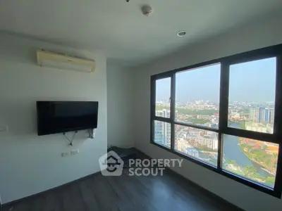 Modern living room with large windows offering stunning city view, wall-mounted TV, and sleek flooring.