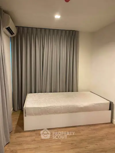 Cozy bedroom with minimalist design featuring a single bed and elegant curtains.