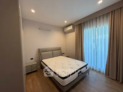 Modern bedroom with large window and elegant curtains, featuring a comfortable bed and wooden flooring.