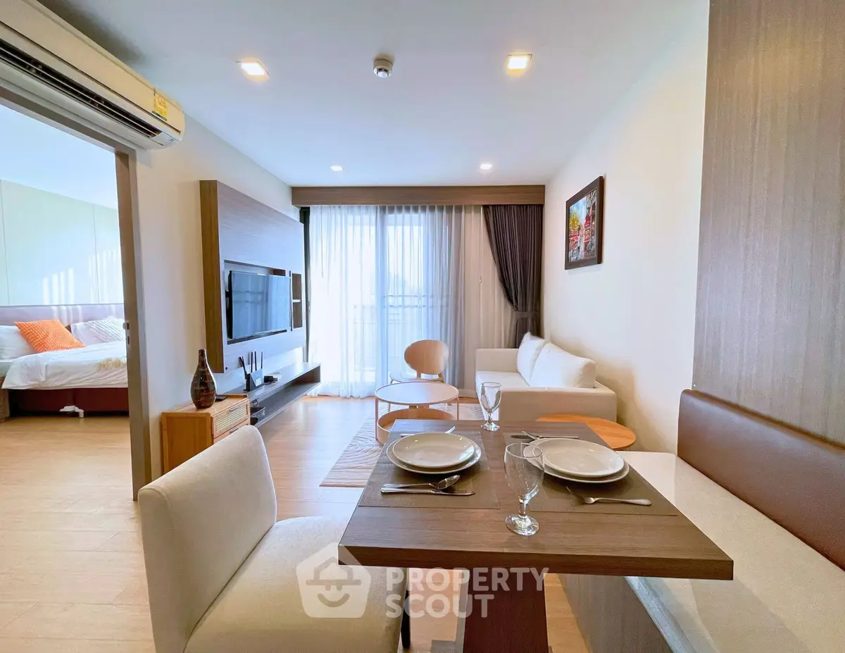 Modern open-plan living room with dining area and bedroom view, featuring stylish decor and natural light.
