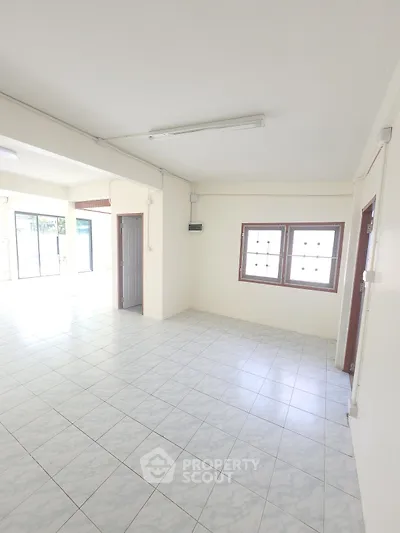 Spacious and bright living room with tiled flooring and large windows.