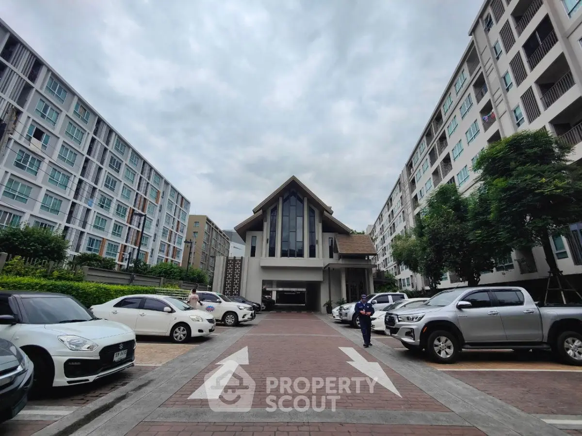 Modern apartment complex entrance with parked cars and cloudy sky