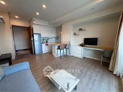 Modern open-plan living room with kitchen, featuring sleek furniture and natural light.