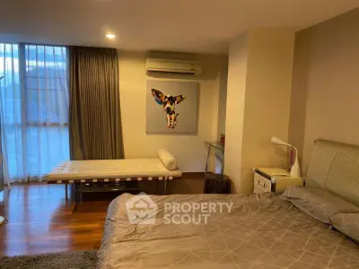 Spacious bedroom with modern decor and large window offering natural light.
