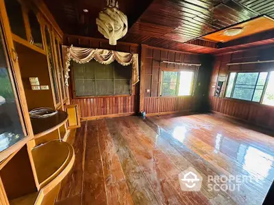 Spacious wooden living room with large windows and unique ceiling light fixture