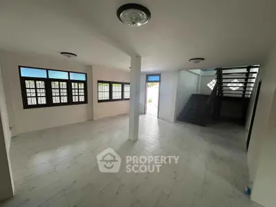 Spacious open-plan living area with large windows and staircase, perfect for modern living.