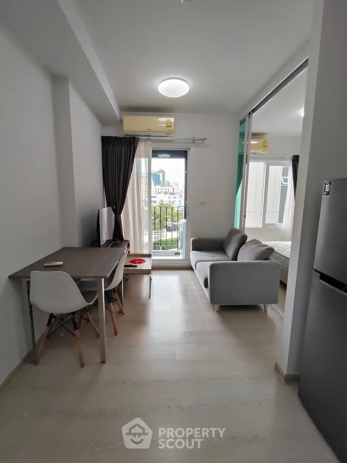 Modern apartment interior with open living room and dining area, featuring a city view balcony.