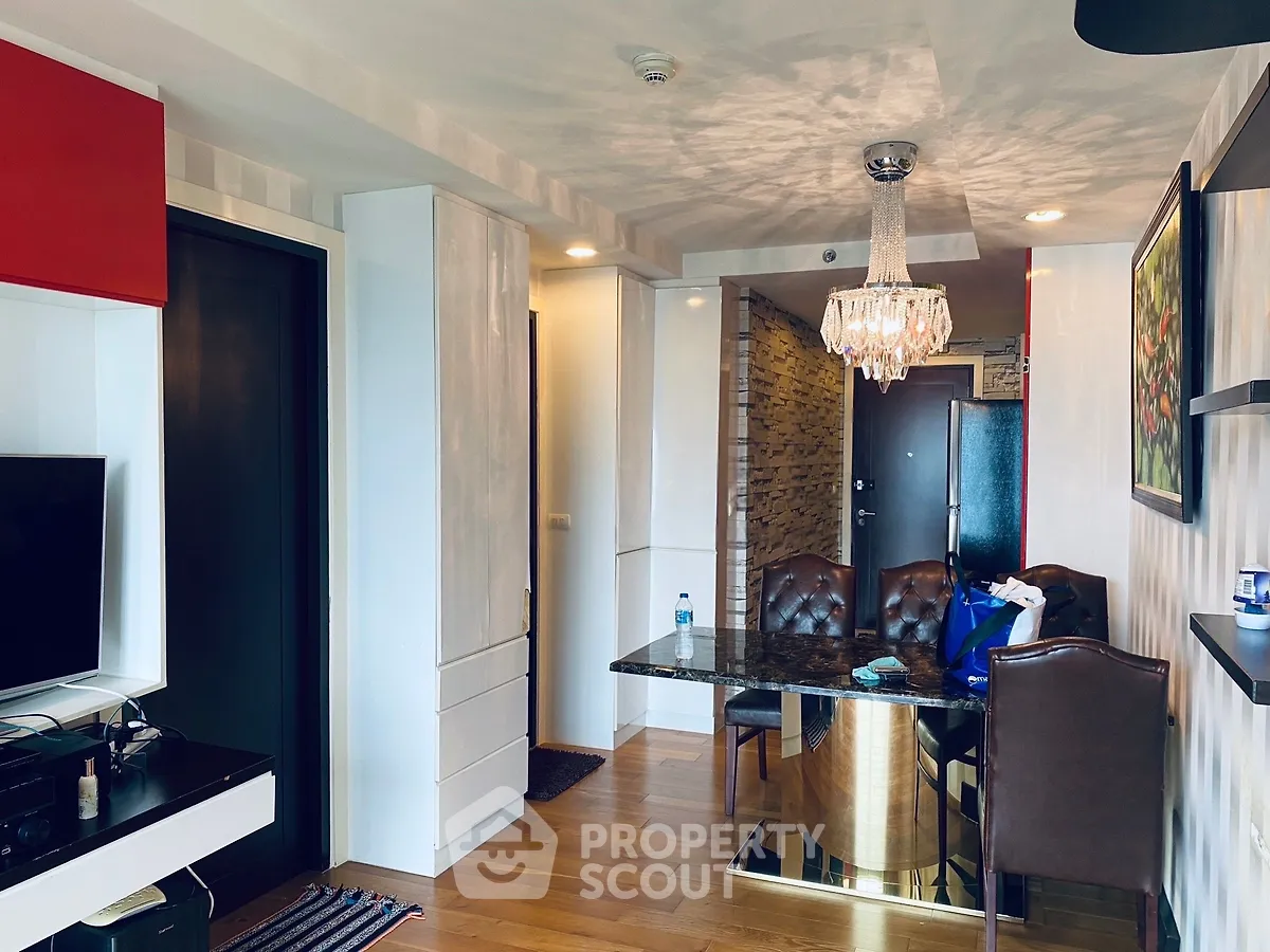 Stylish modern living room with elegant chandelier and dining area in a contemporary apartment.