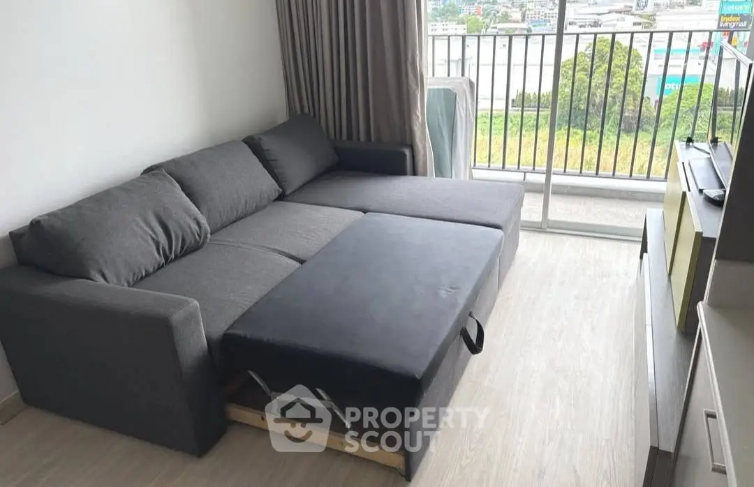 Modern living room with sleek gray sofa bed and balcony view, perfect for urban living.