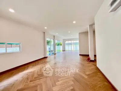 Spacious living room with elegant wooden flooring and large windows for natural light.