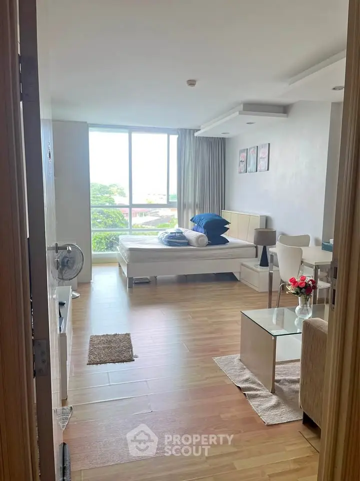 Spacious studio apartment with modern decor and large window view.
