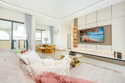 Luxurious living room with elegant decor and large TV, featuring a spacious open layout and stylish furniture.