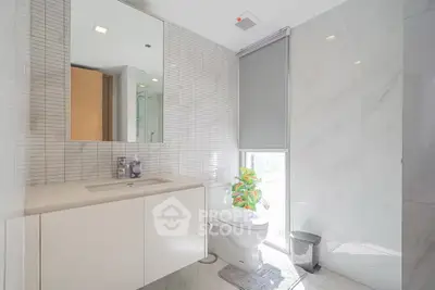 Modern bathroom with sleek design, featuring a large mirror, elegant sink, and natural light.