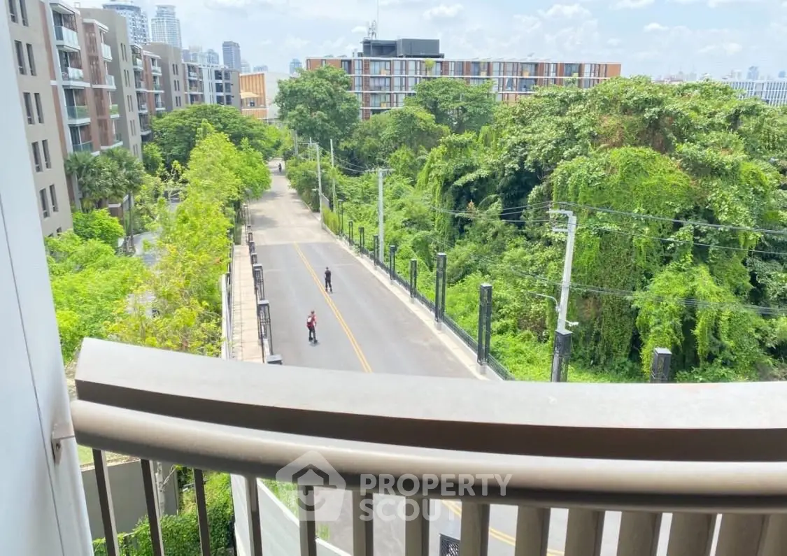 Scenic view from balcony overlooking lush greenery and modern buildings, perfect for urban nature lovers.