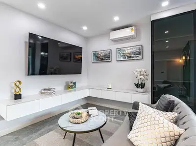 Modern living room with sleek design, featuring a large TV and stylish decor.