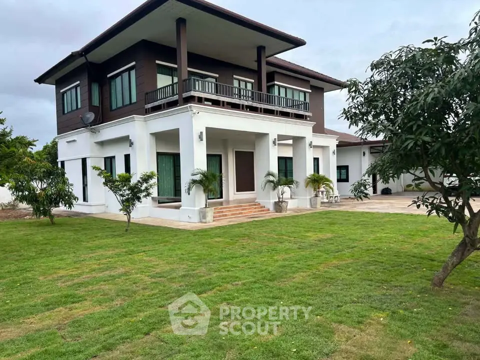 Stunning two-story modern house with lush green lawn and spacious outdoor area.