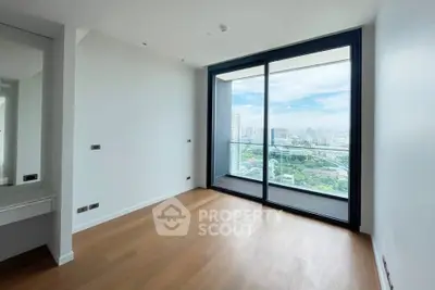Spacious modern room with large glass doors opening to a balcony with stunning city views.