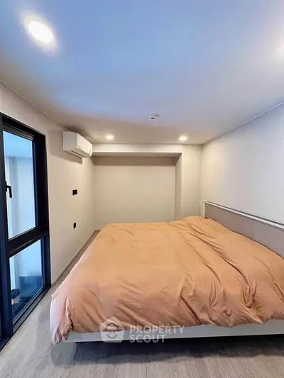 Modern bedroom with large window and cozy bedding in a stylish apartment.
