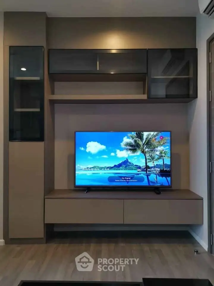 Modern living room with sleek TV unit and tropical beach scene on screen.
