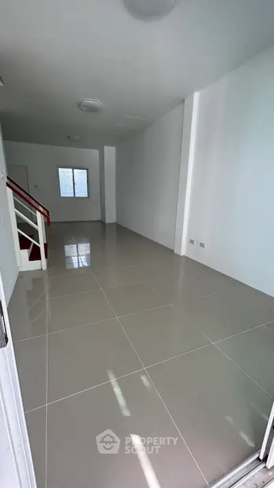 Spacious open-plan living area with sleek tiled flooring and modern staircase, perfect for customization.