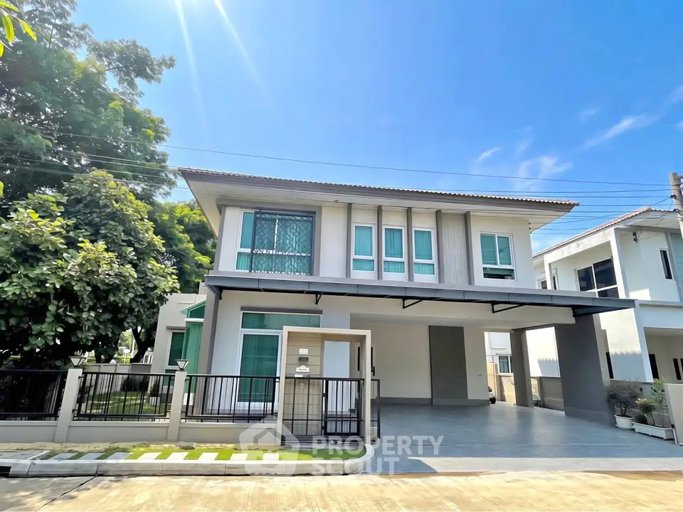 Modern two-story house with spacious driveway and lush greenery under a clear blue sky.