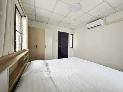Cozy bedroom with air conditioning and ample natural light, featuring a comfortable bed and built-in wardrobe.