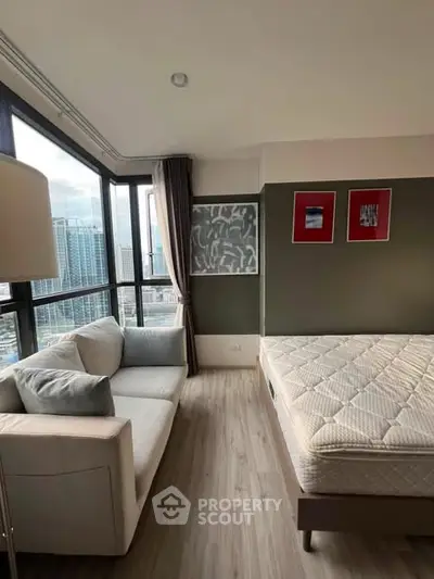 Modern bedroom with city view, featuring a cozy sofa and stylish decor, perfect for urban living.