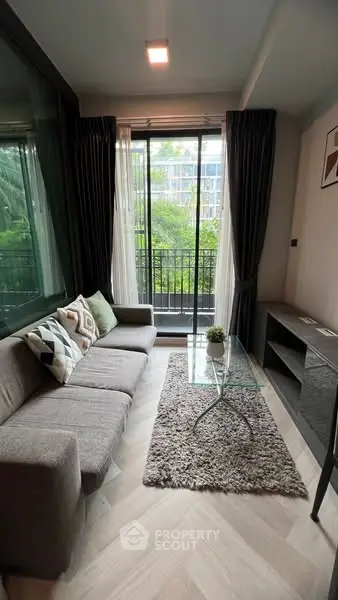 Modern living room with cozy sofa and glass coffee table overlooking lush greenery.