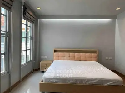 Spacious bedroom with large windows and modern bed frame in a bright apartment.