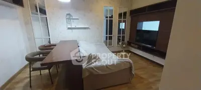 Cozy living room with modern decor and wooden flooring, featuring a stylish TV unit and comfortable seating.
