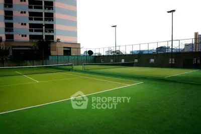 Spacious tennis court in modern residential complex with city views, perfect for sports enthusiasts.