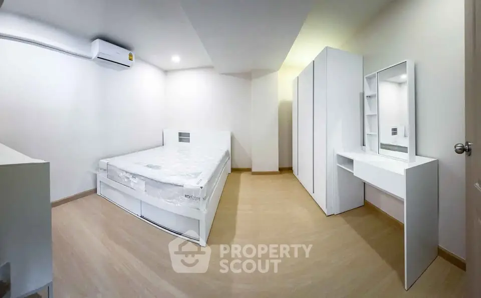 Spacious modern bedroom with minimalist white furniture and ample storage space.