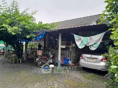Charming rustic house with carport and lush greenery in a serene setting.