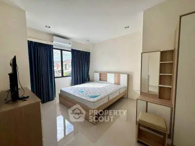 Spacious bedroom with modern furniture and large windows for natural light.