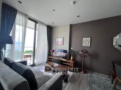 Modern living room with stylish decor and large windows opening to a balcony with a view.